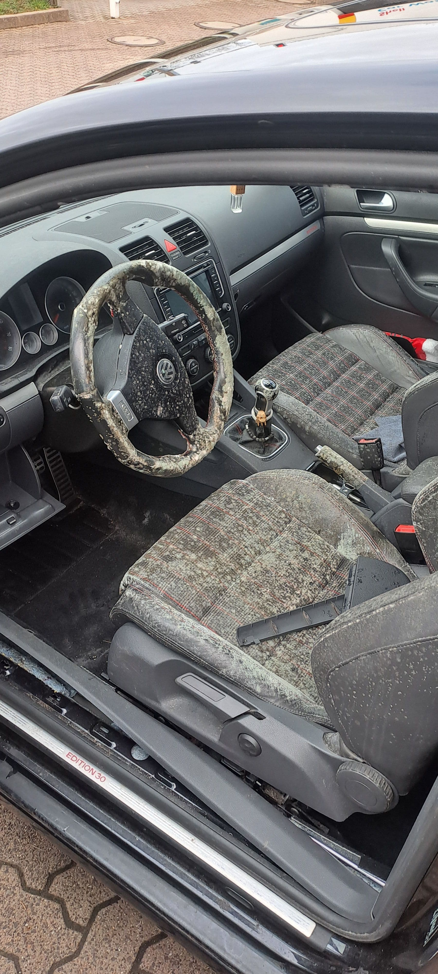 Stark verschmutzter Innenraum eines VW Golf: verstaubtes Armaturenbrett, fleckige Stoffsitze